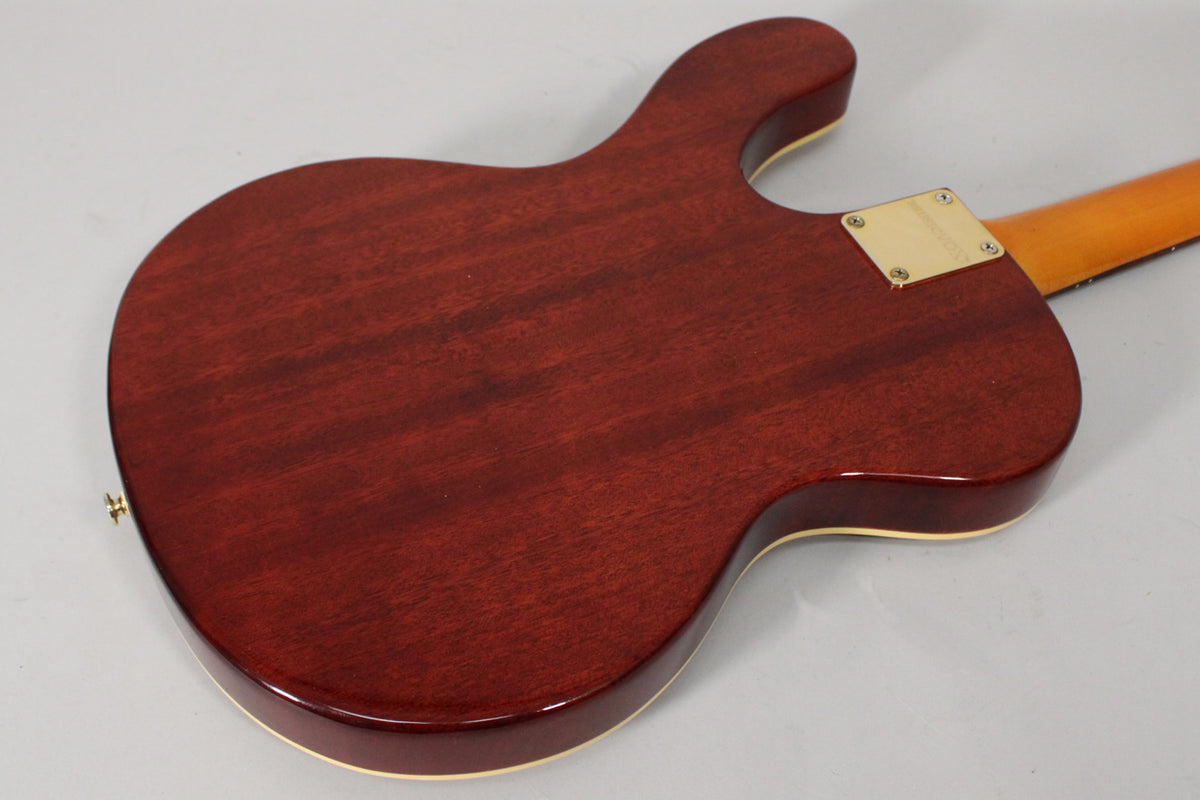 The guitar's back is a dark reddish-brown with visible wood grain, cream binding, and a gold neck plate.