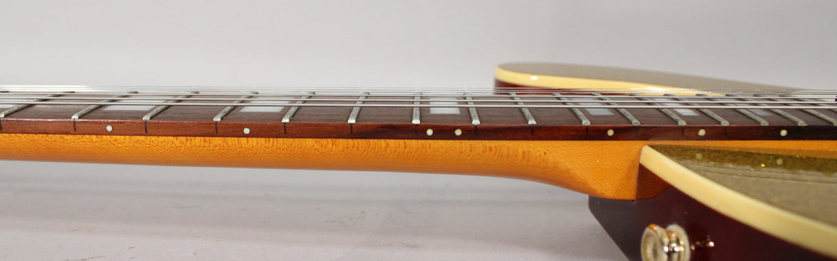 Close-up of the guitar's neck and fretboard from the side, showing the dark wood fretboard with white dot inlays and frets.