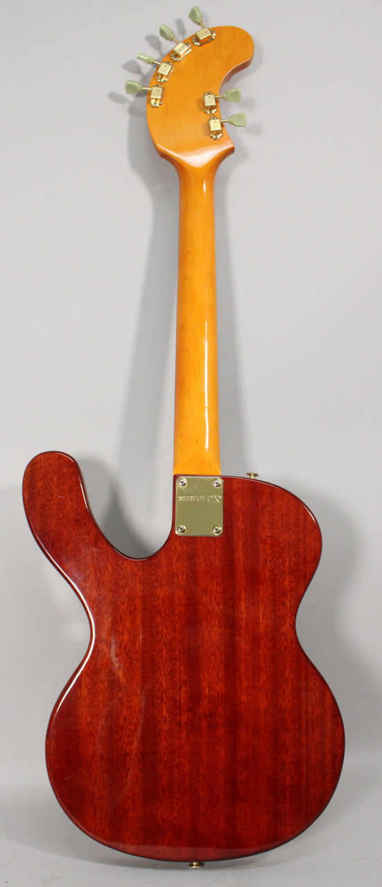 The guitar's back, showing a rich reddish-brown wood grain body, a glossy amber neck, and a gold neck plate.