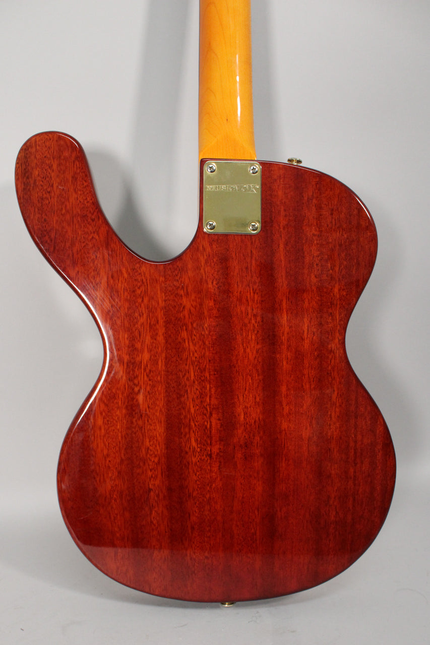 The guitar's back shows a rich, reddish-brown wood grain with a glossy finish, a gold neck plate, and a matching strap button.
