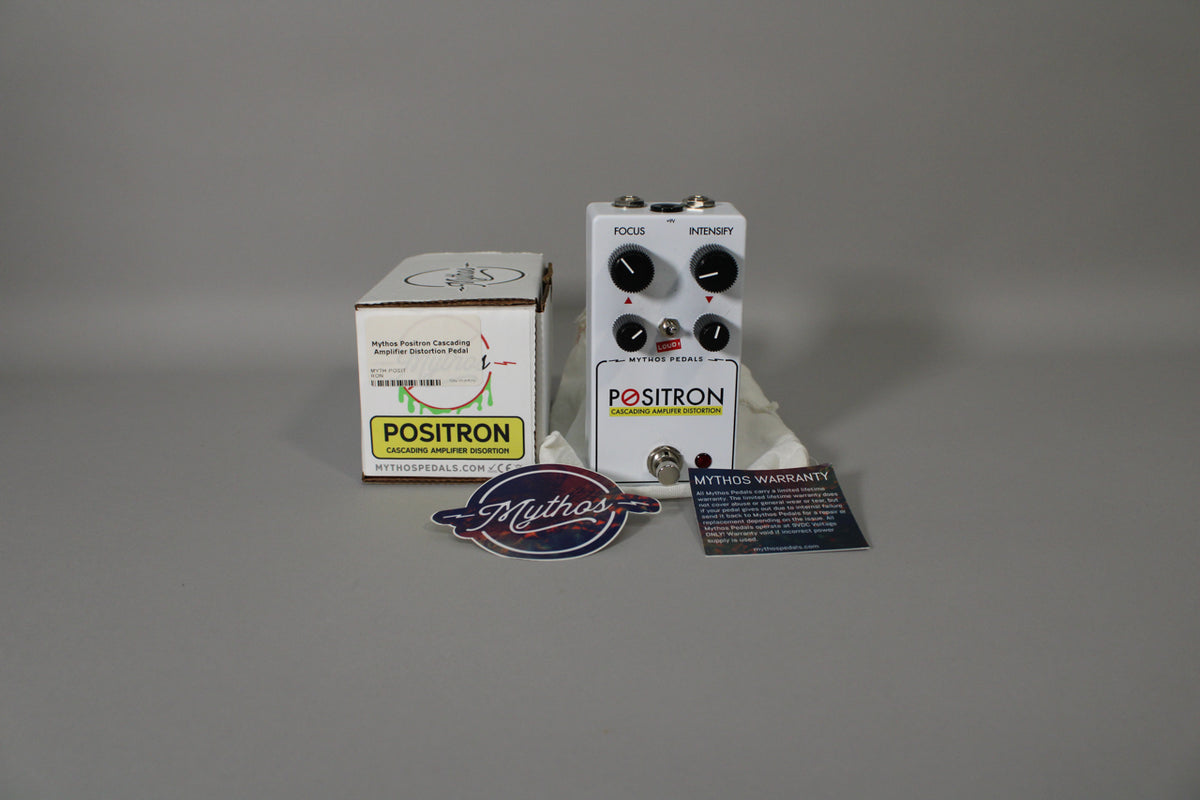 A white guitar pedal with four black knobs, two mini-toggle switches, and a footswitch, shown with its box and papers.