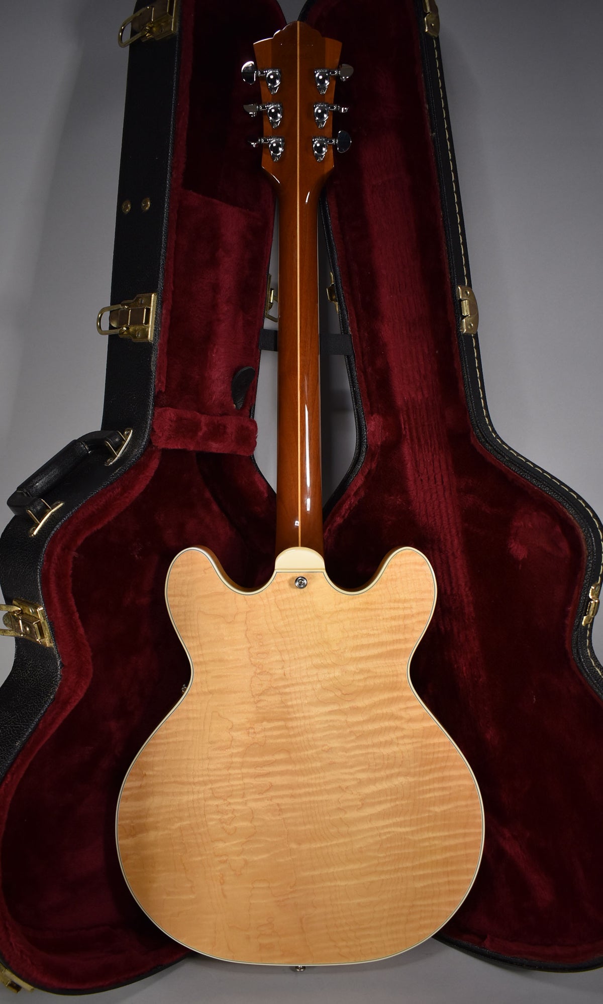 The guitar's natural finish back and neck are visible, showing a flame maple grain and six chrome tuners on the headstock.