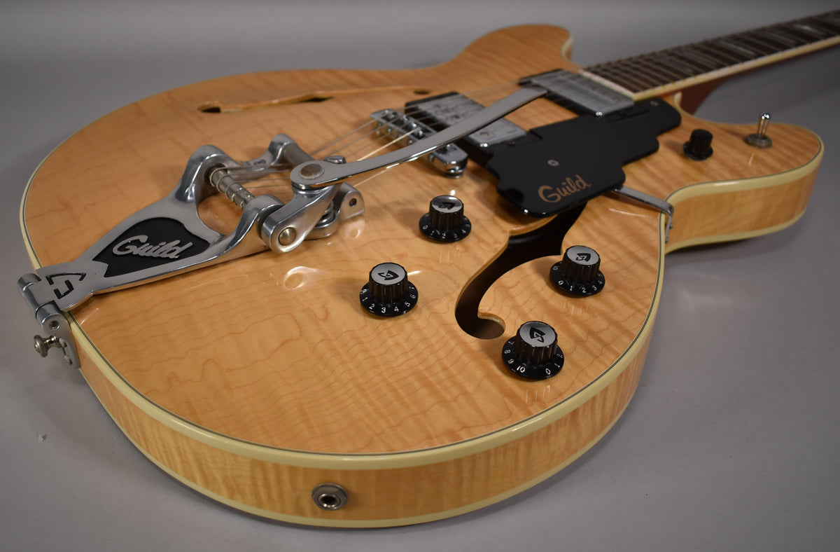 Close-up of the natural finish, flame maple body, showing the Bigsby vibrato, black pickguard, and four black control knobs.