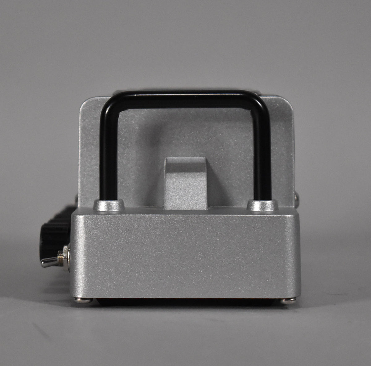 The silver-grey mini amp head is viewed from the front, showing a black handle, a toggle switch, and a black knob on the left.