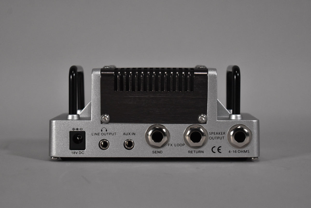 Rear view of the silver and black guitar head, showing the 18V DC input, Line Out, Aux In, FX Loop, and Speaker Out jacks.