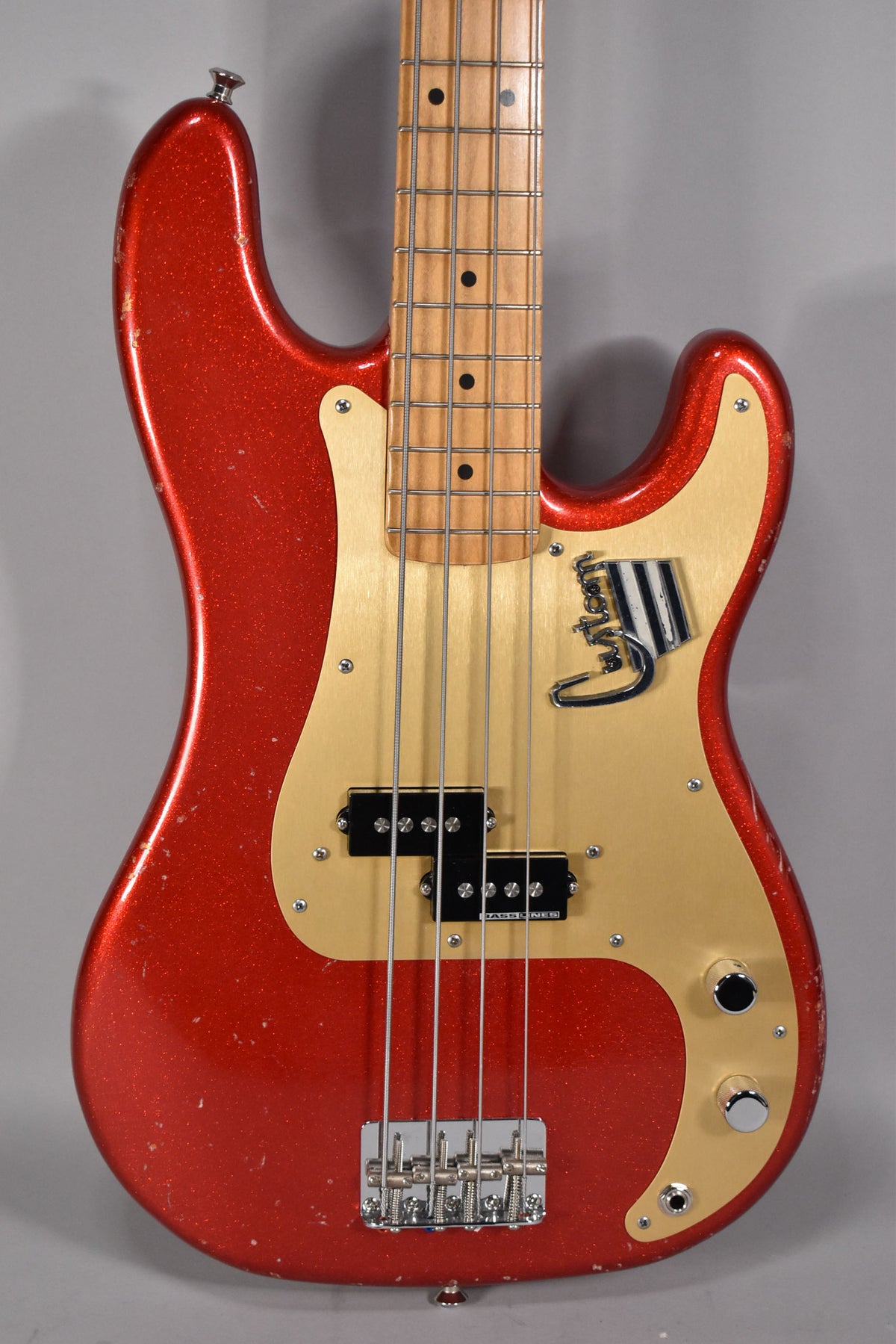 Aged red sparkle bass, body and neck visible, with a gold pickguard, split pickup, and chrome bridge.