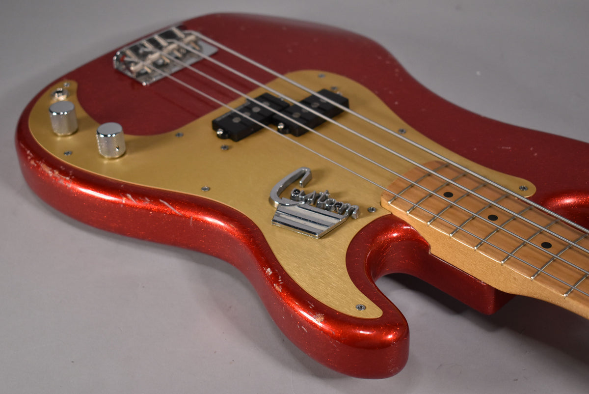 The red sparkle bass body, with a gold pickguard and chrome hardware, shows visible wear and checking.