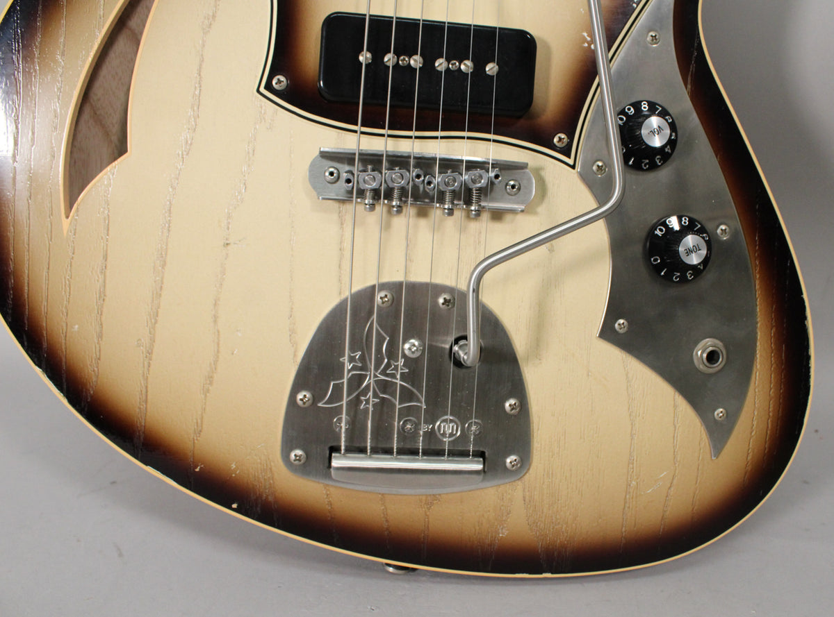Close-up of the guitar's lower body, showing the P90 pickup, brushed metal bridge, tremolo, and control plate with two black knobs.