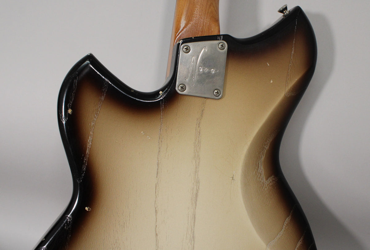 The back of a semi-hollow guitar with a toasted marshmallow burst finish, showing heavy wear, checking, and a four-screw neck plate.