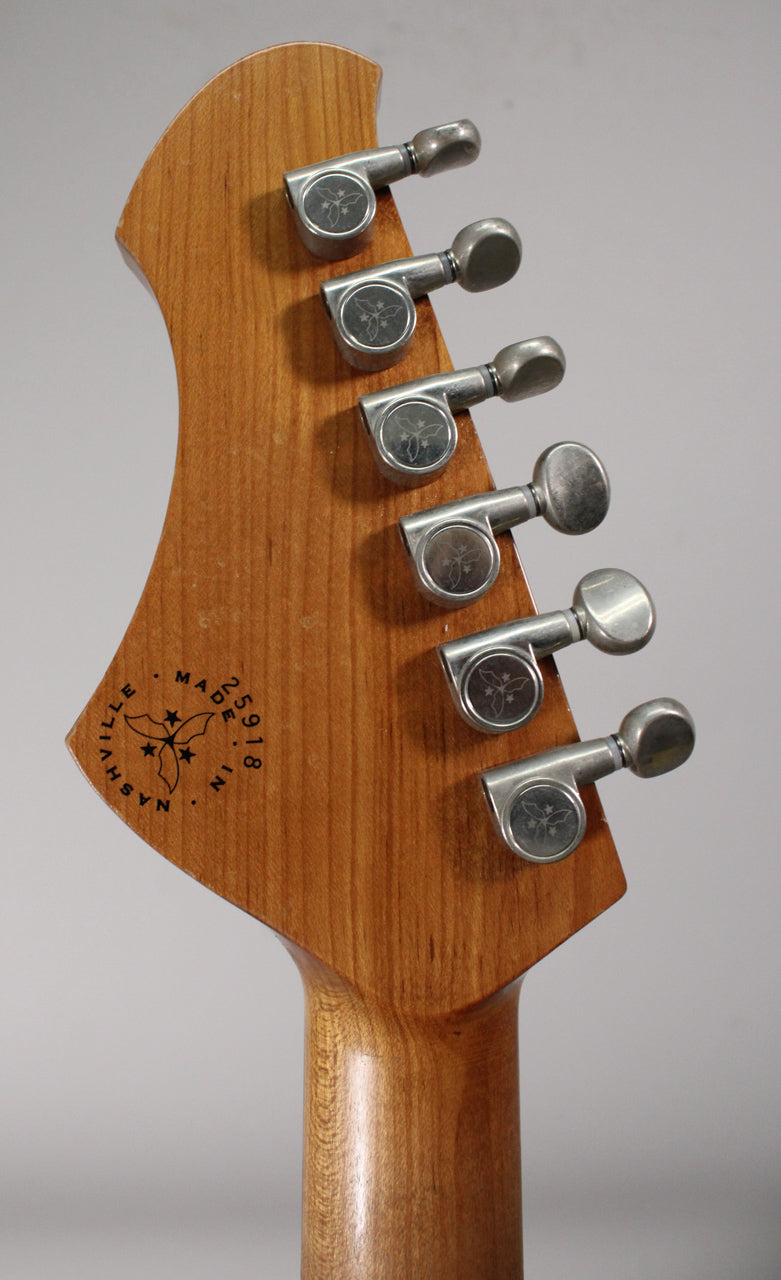The back of a light-aged, caramel-colored guitar headstock with six distressed silver tuners, angled from the bottom left.