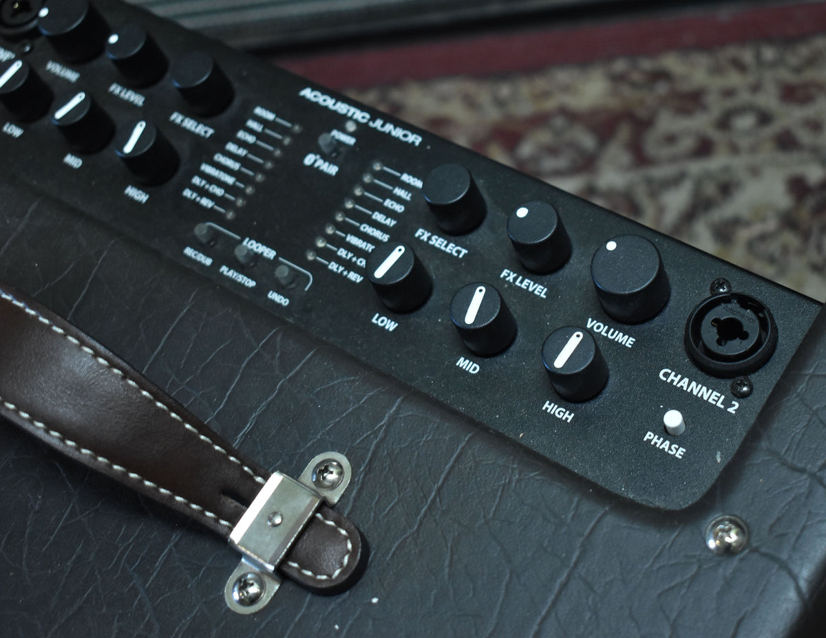 Close-up of the amp's black control panel with numerous knobs and buttons, and a dark brown leather handle with white stitching.