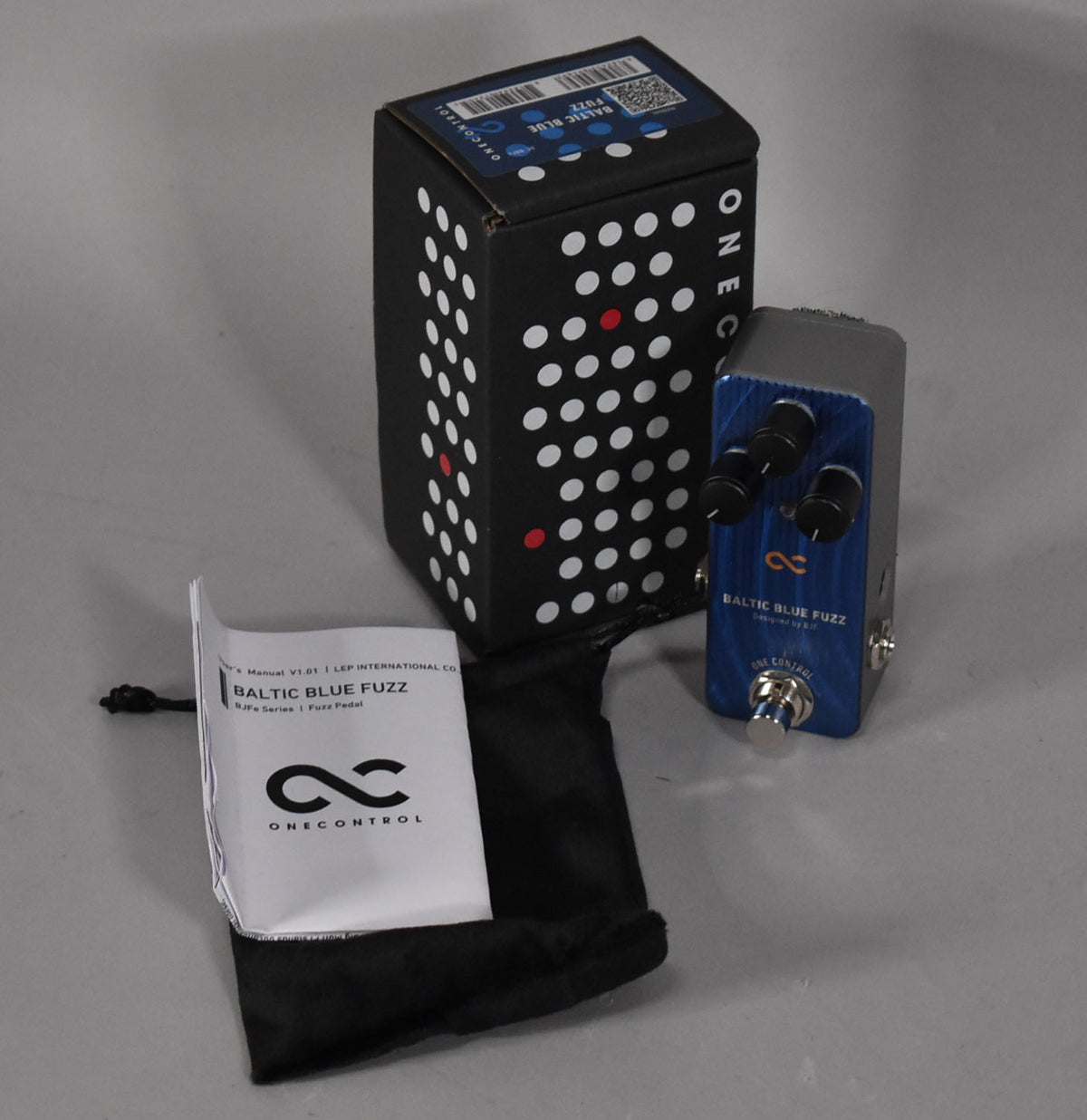 The Baltic Blue Fuzz pedal is shown with its black box and manual, featuring a blue faceplate and three black control knobs.
