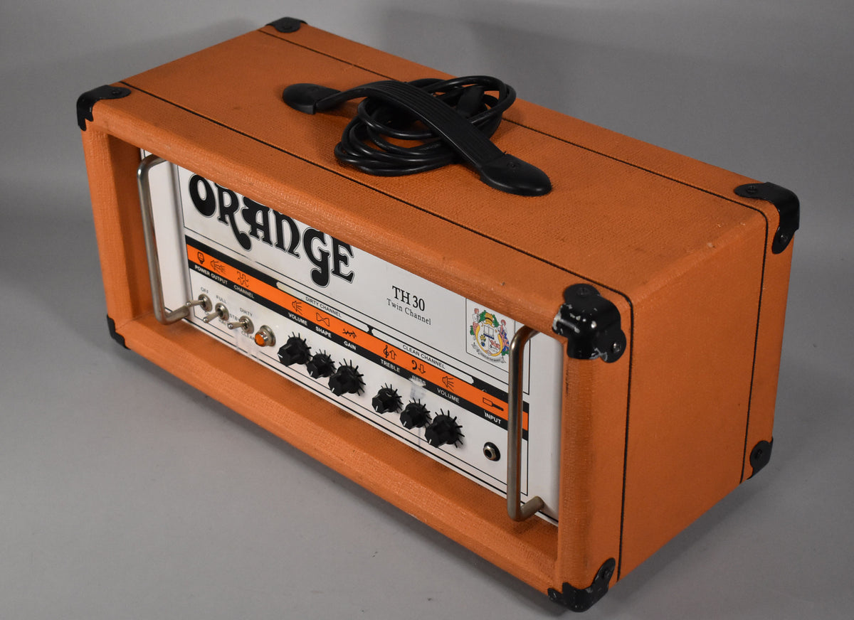 An orange amplifier head with a white control panel, black knobs, and a black top handle, viewed from the front-right.