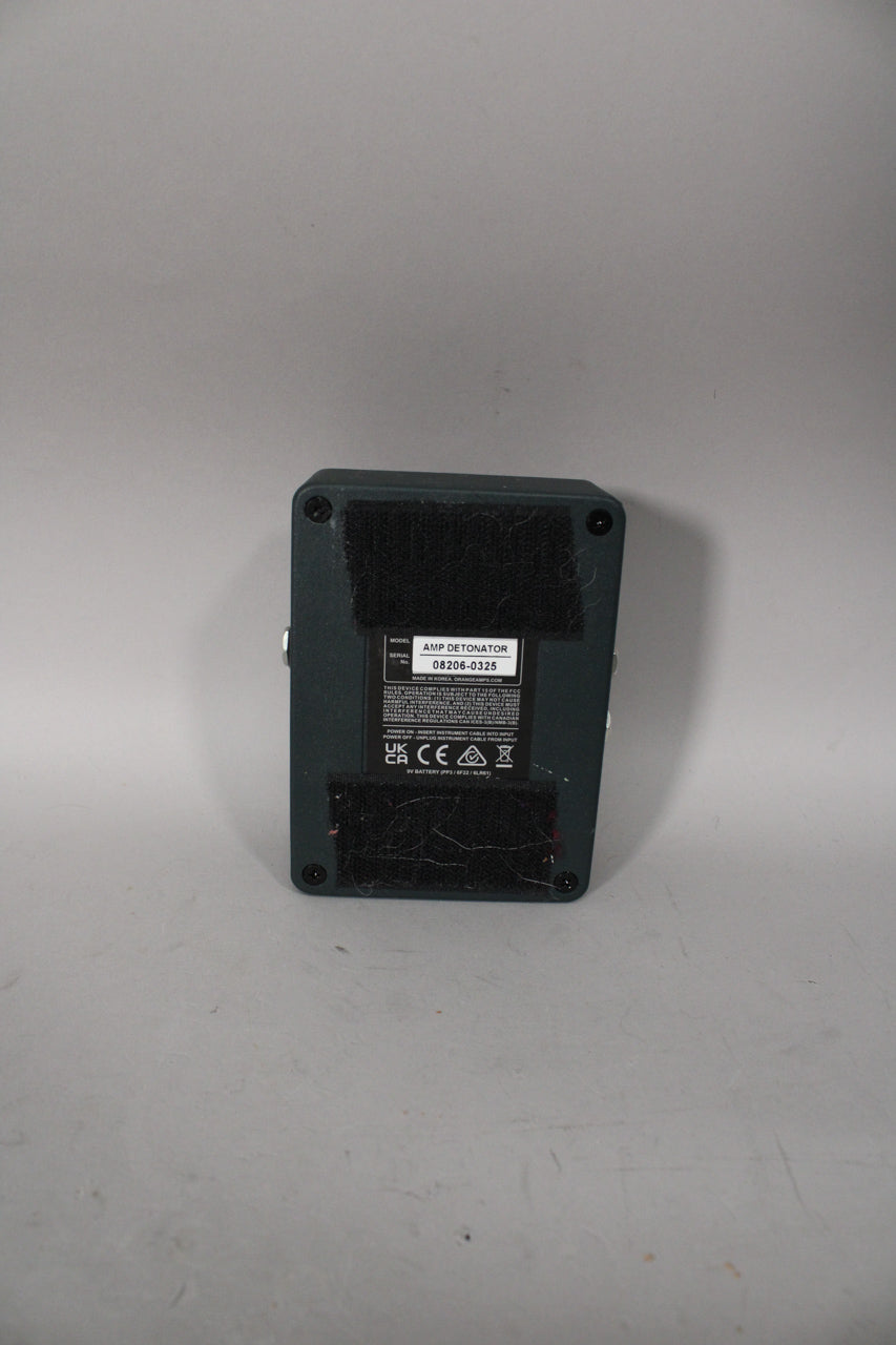 The dark gray pedal is seen from the back, with black velcro strips covering most of the base and a central info sticker.