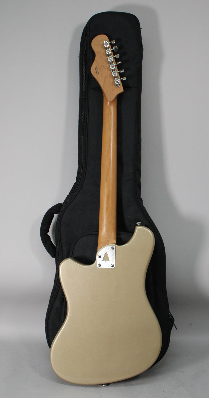 The back of a sandstone baritone guitar with a light wood neck, chrome tuners, and a tree logo on the neck plate.