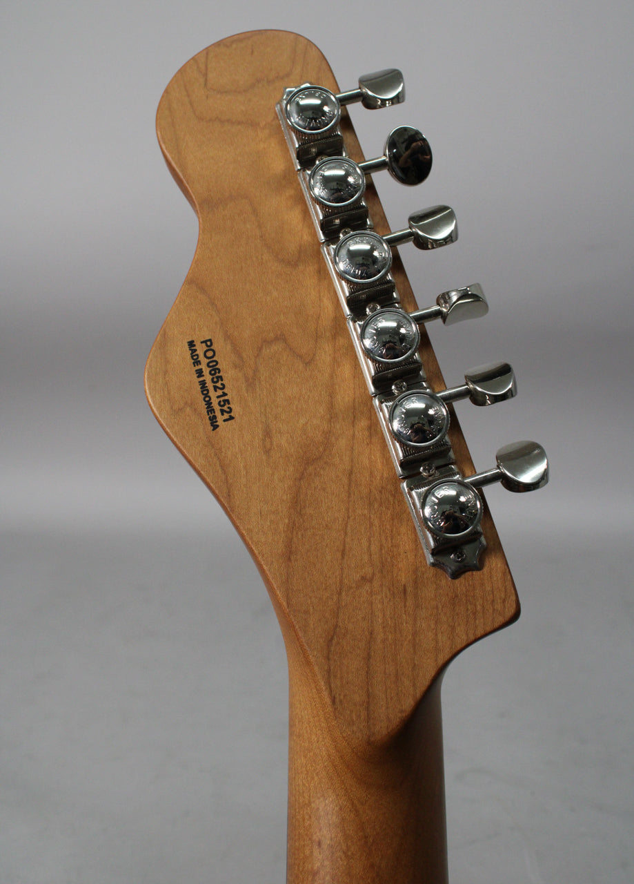 The back of a light brown wooden headstock and neck, angled right, with six chrome tuners in a 6-in-line configuration.