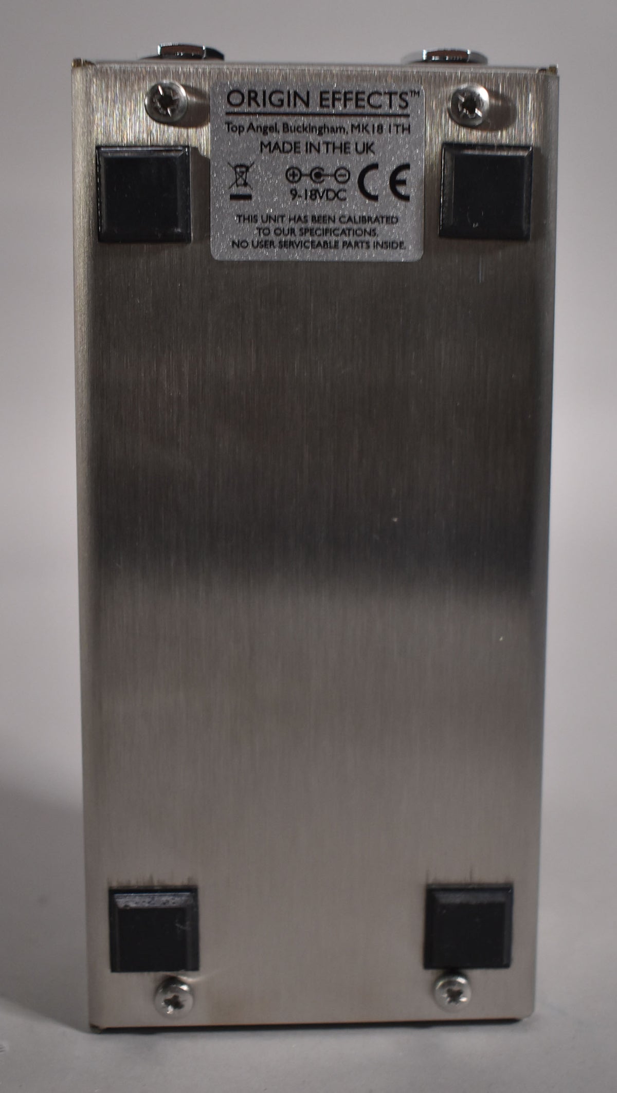 The pedal's brushed metal underside is visible, with four black rubber feet and a silver label at the top.