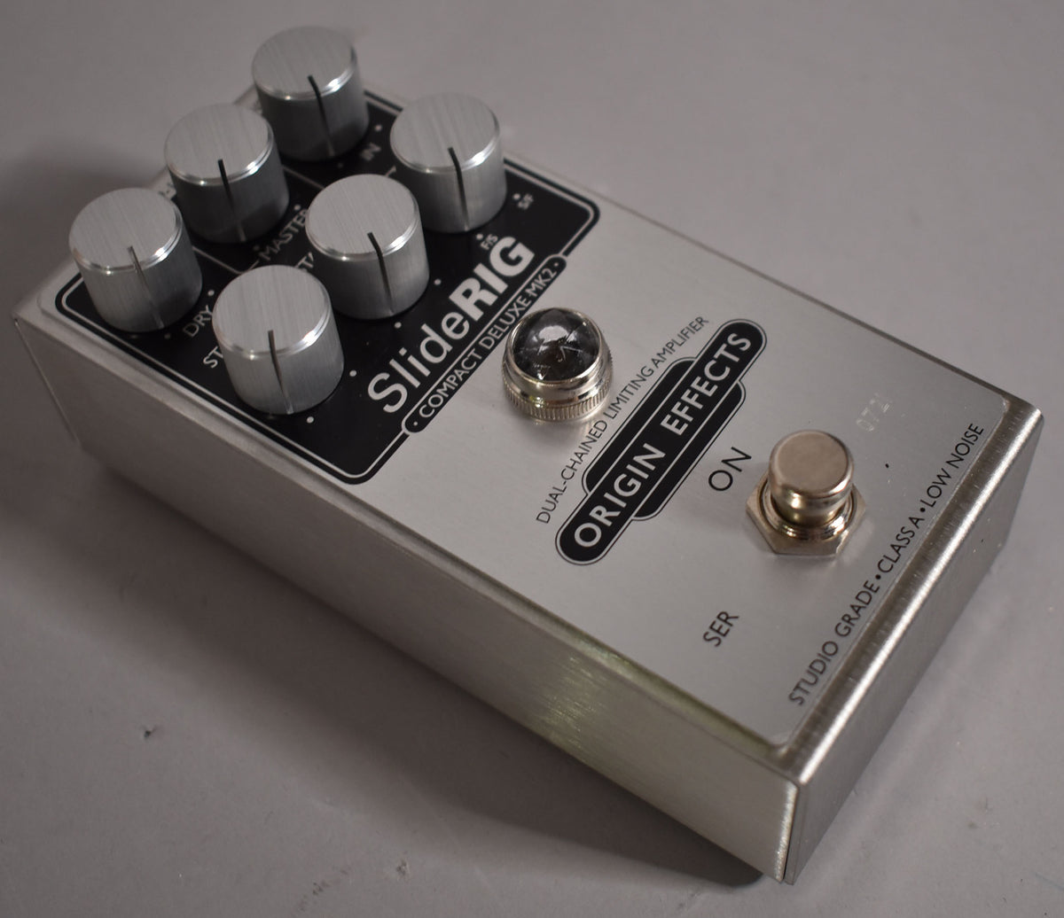 A brushed silver guitar pedal with six silver knobs, a clear jewel light, and a silver footswitch, viewed from the top-right.