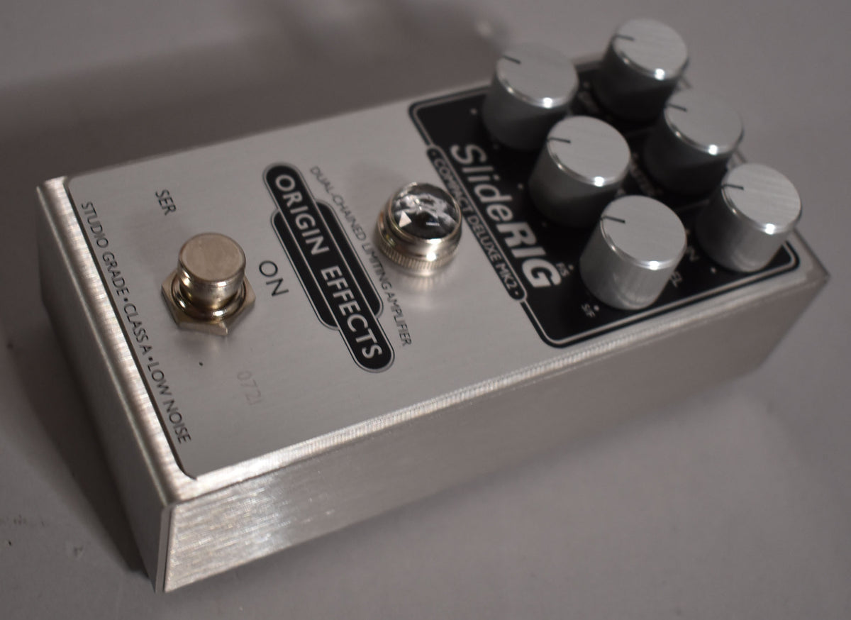 A brushed silver effect pedal, angled from the front-right, with a footswitch, a jewel lamp, and six silver control knobs.