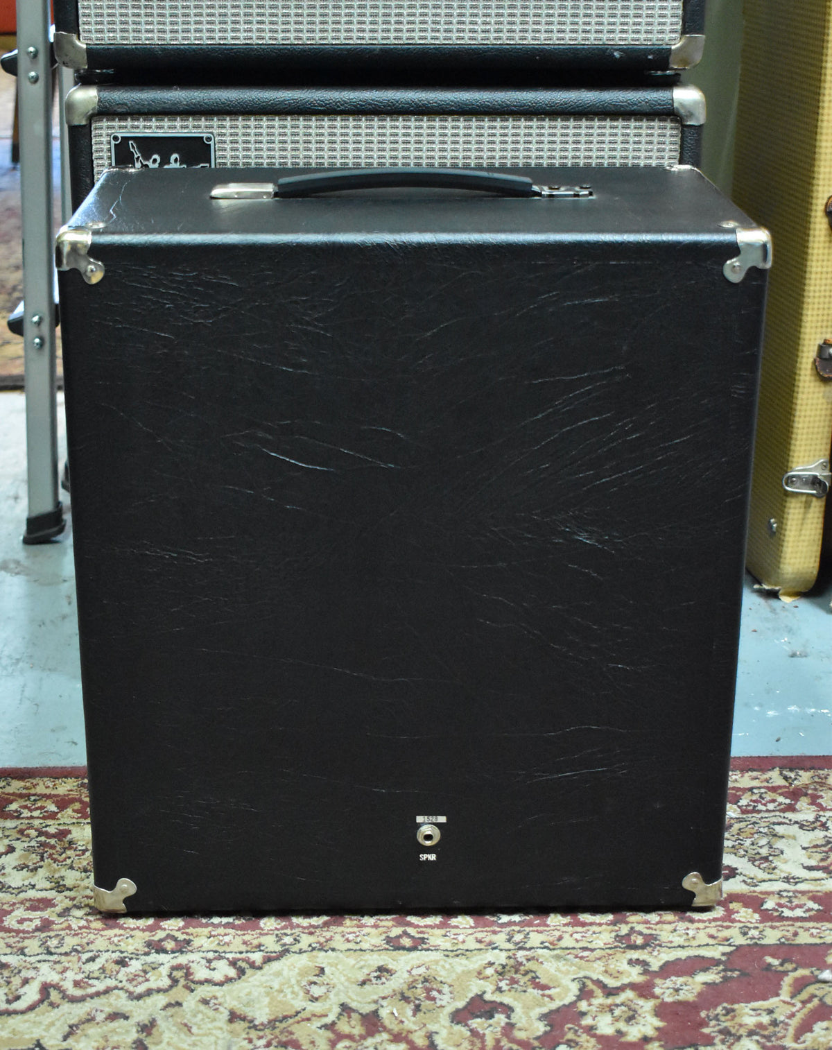 The black textured speaker cabinet is viewed from the rear, showing a single speaker input jack and some scuffs on the tolex.