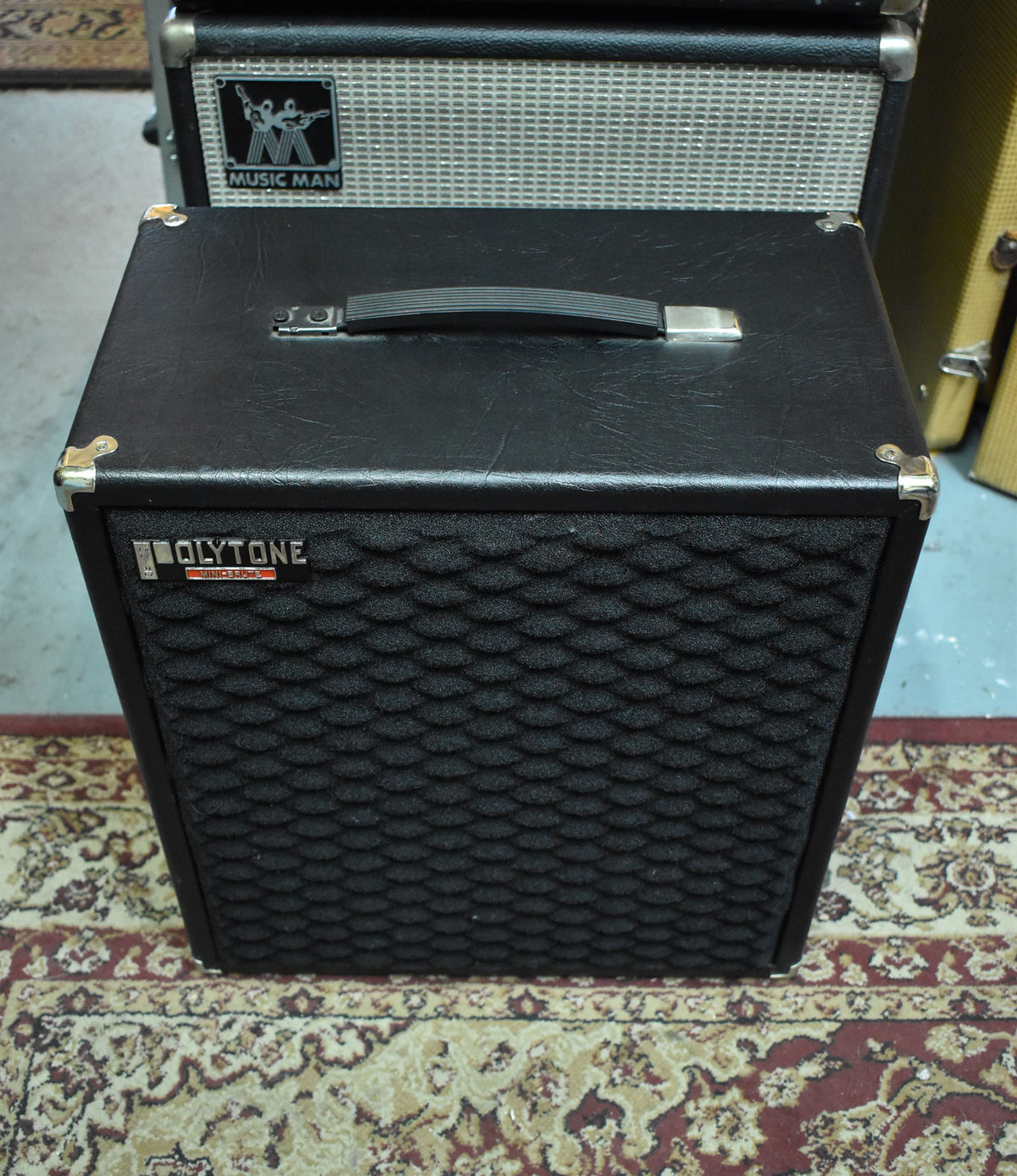 The black vinyl-covered speaker cabinet, seen from the front, has a textured black foam grille and a top-mounted handle.