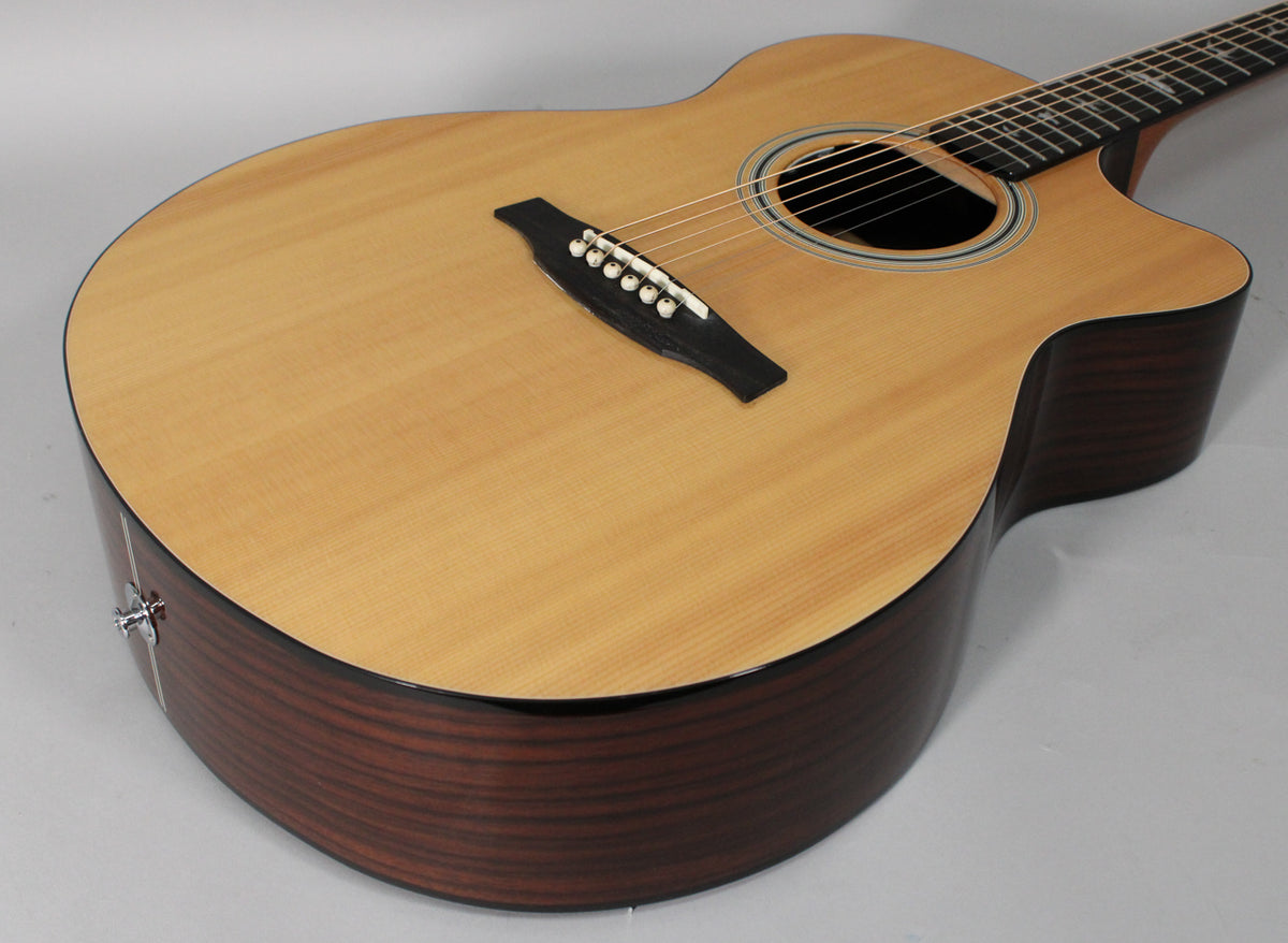 The acoustic-electric guitar's light wood top and dark striped sides are angled, showing the bridge, soundhole, and a strap button.
