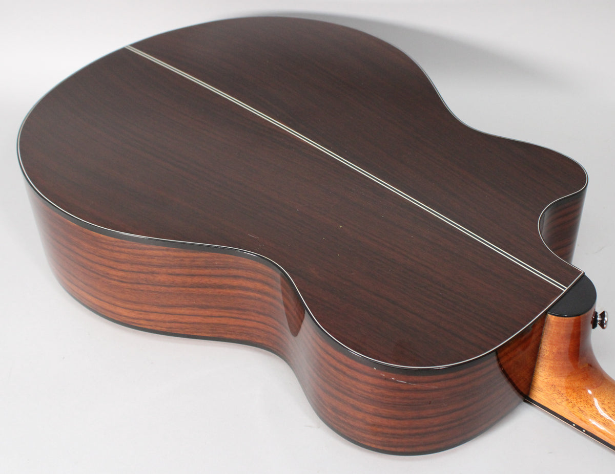 The guitar's dark rosewood back and sides are shown from an upper-rear angle, with a cutaway and two thin white back strips.