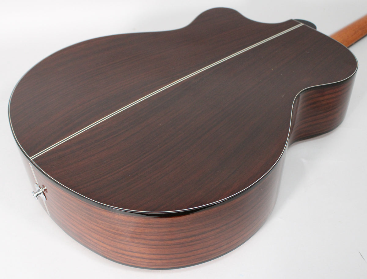 The guitar's dark rosewood back and sides are shown from a high angle, with a chrome endpin jack visible on the lower bout.