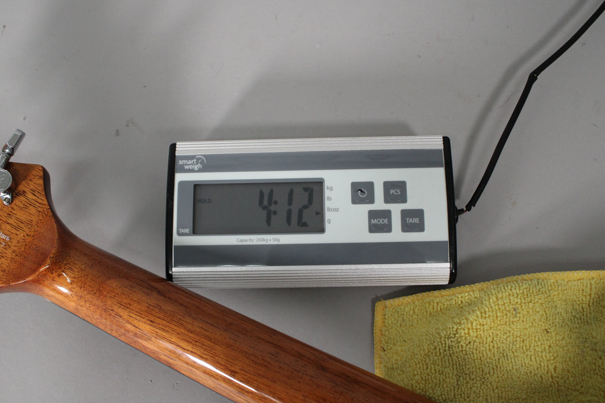 The guitar's glossy brown neck and headstock are visible, with a digital scale displaying "4.12" in the background.