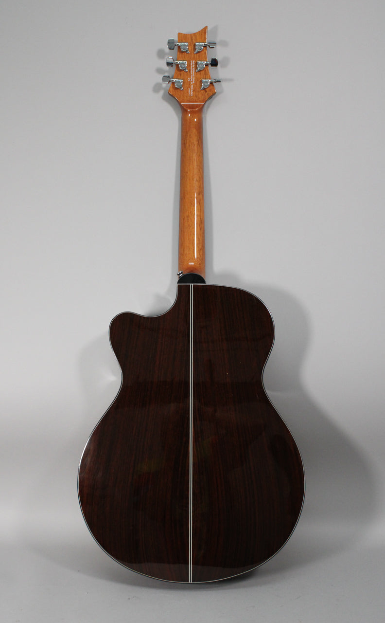 The guitar's dark rosewood back and sides feature a light center strip, with a glossy light brown neck and chrome tuners.