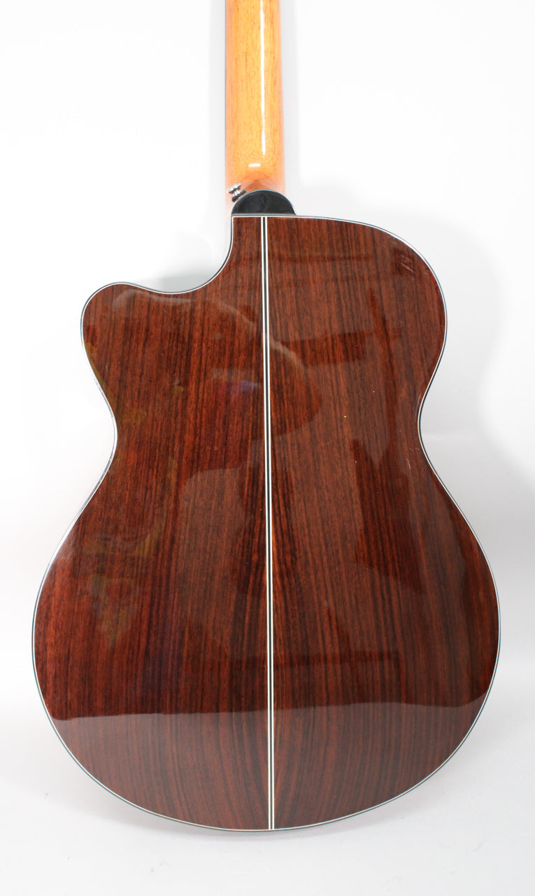 The guitar's glossy dark rosewood back, with a white center strip and binding, is visible from the lower bout to the neck heel.