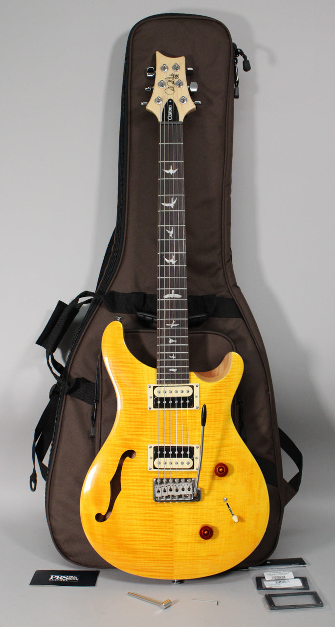 Full-length view of a bright yellow semi-hollow electric guitar with a flamed maple top, cream humbuckers, and red control knobs.