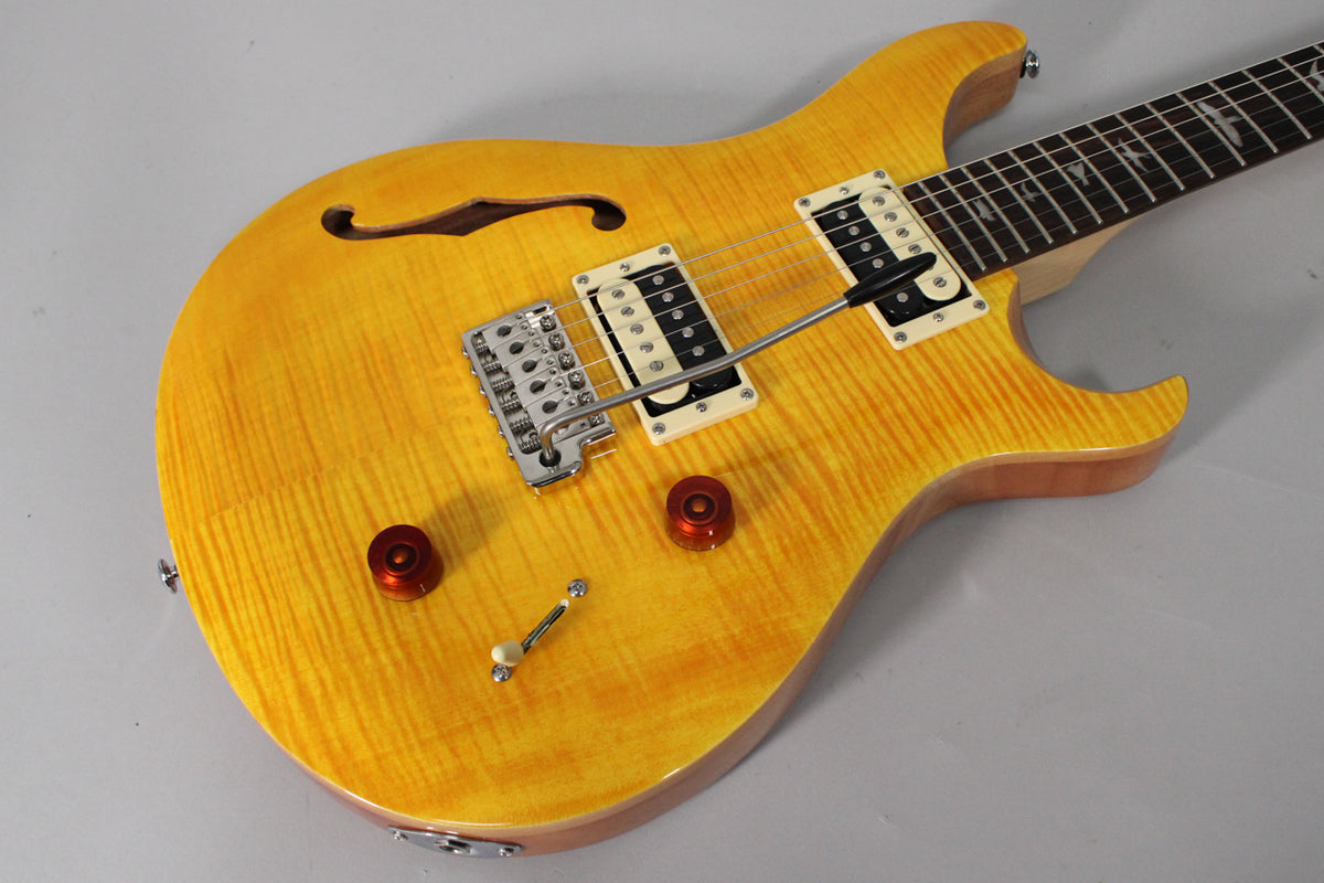 The Santana Yellow semi-hollow guitar, angled from the lower bout, shows a flame maple top, f-hole, and two humbuckers with cream surrounds.