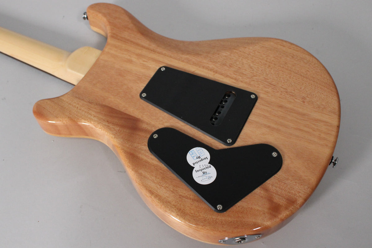 The guitar's back shows a light brown wood grain, with two black control cavity covers and a light-colored neck joint.