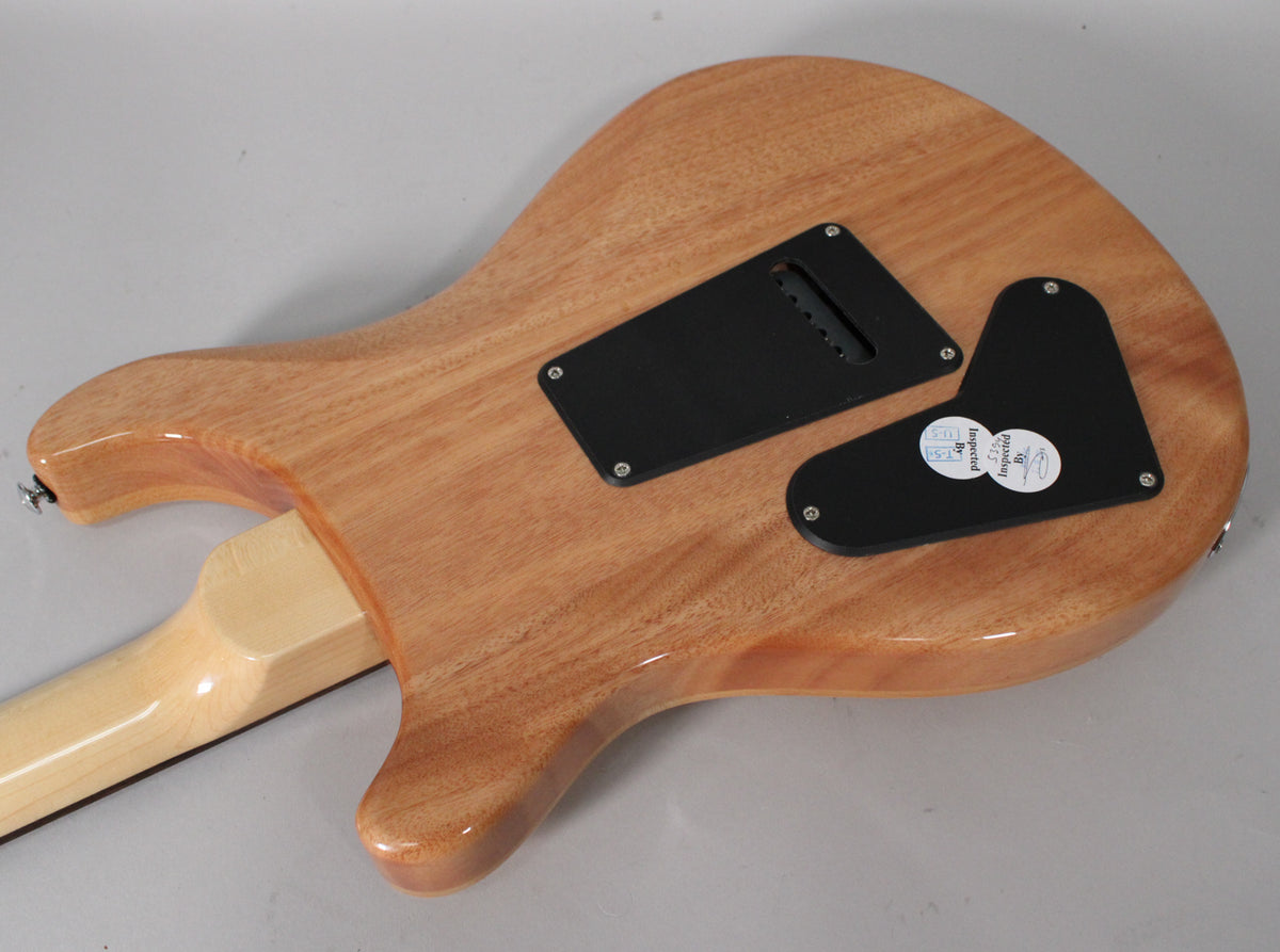 The back of a light brown guitar body, showing two black control cavity covers and a light-colored neck joint.