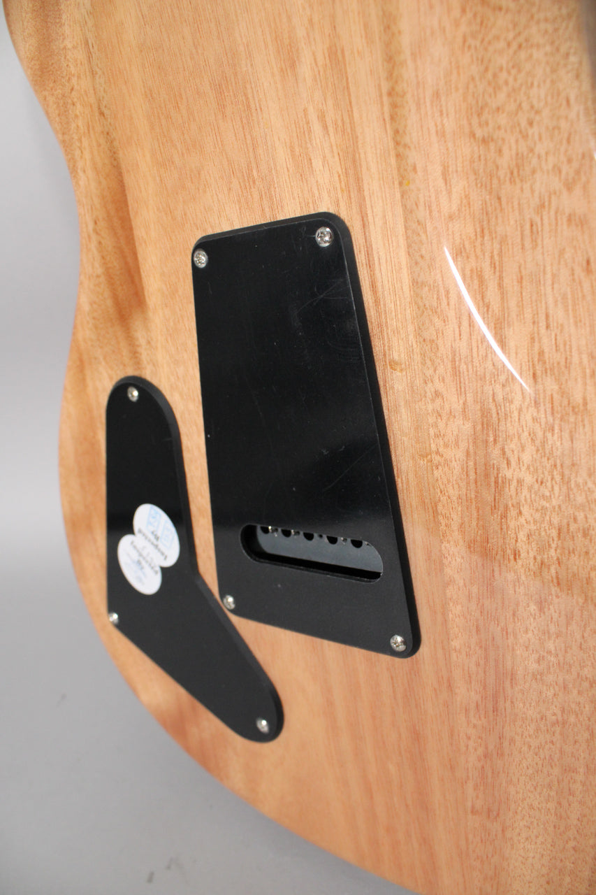 The guitar's back shows a light wood grain with two black control cavity covers, one revealing six string holes.