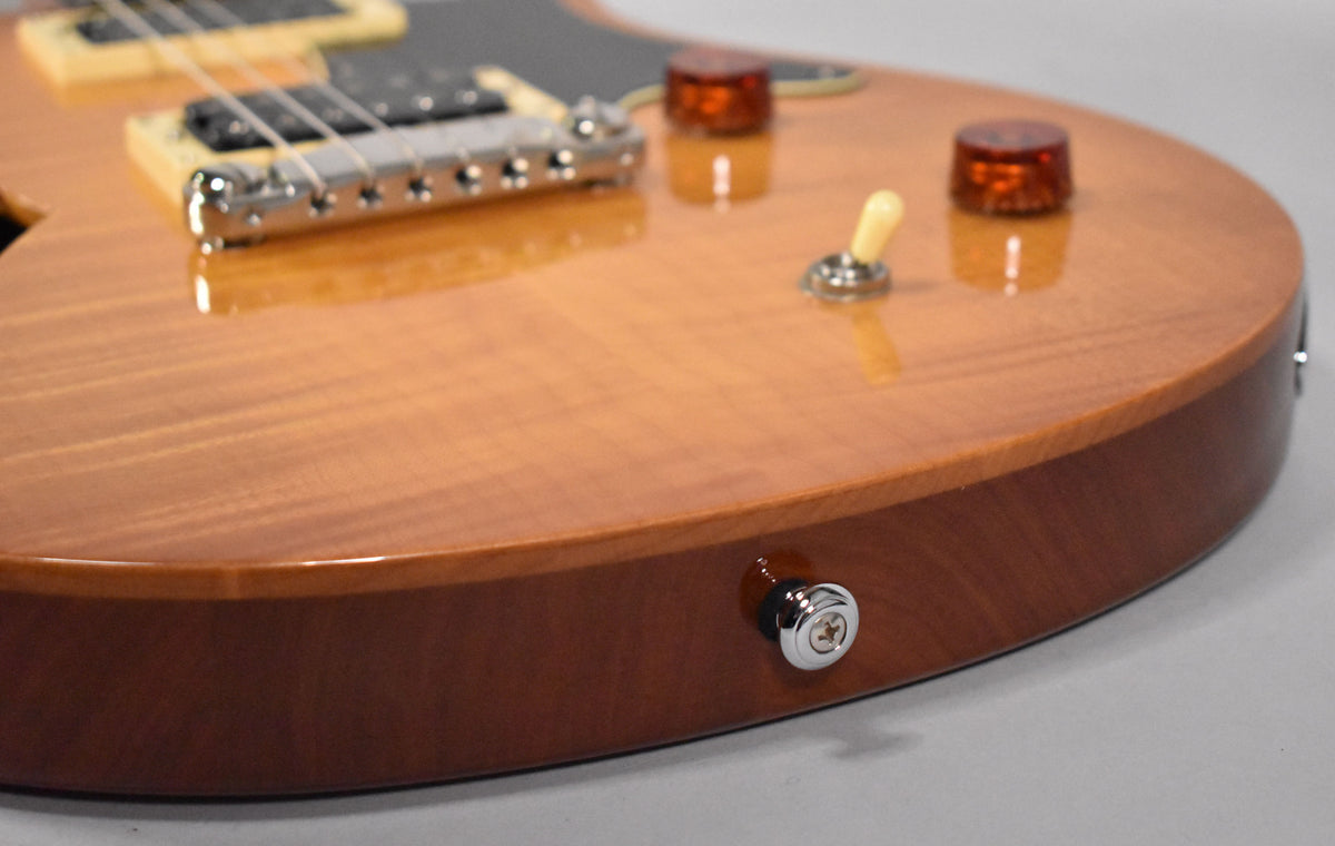 Close-up of the sunburst guitar body, showing the chrome bridge, cream pickup selector, amber control knobs, and a chrome strap button.
