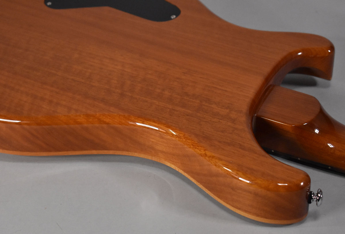 The back of a glossy, reddish-brown guitar body with visible wood grain, showing the lower bout and neck joint, with a chrome strap button.