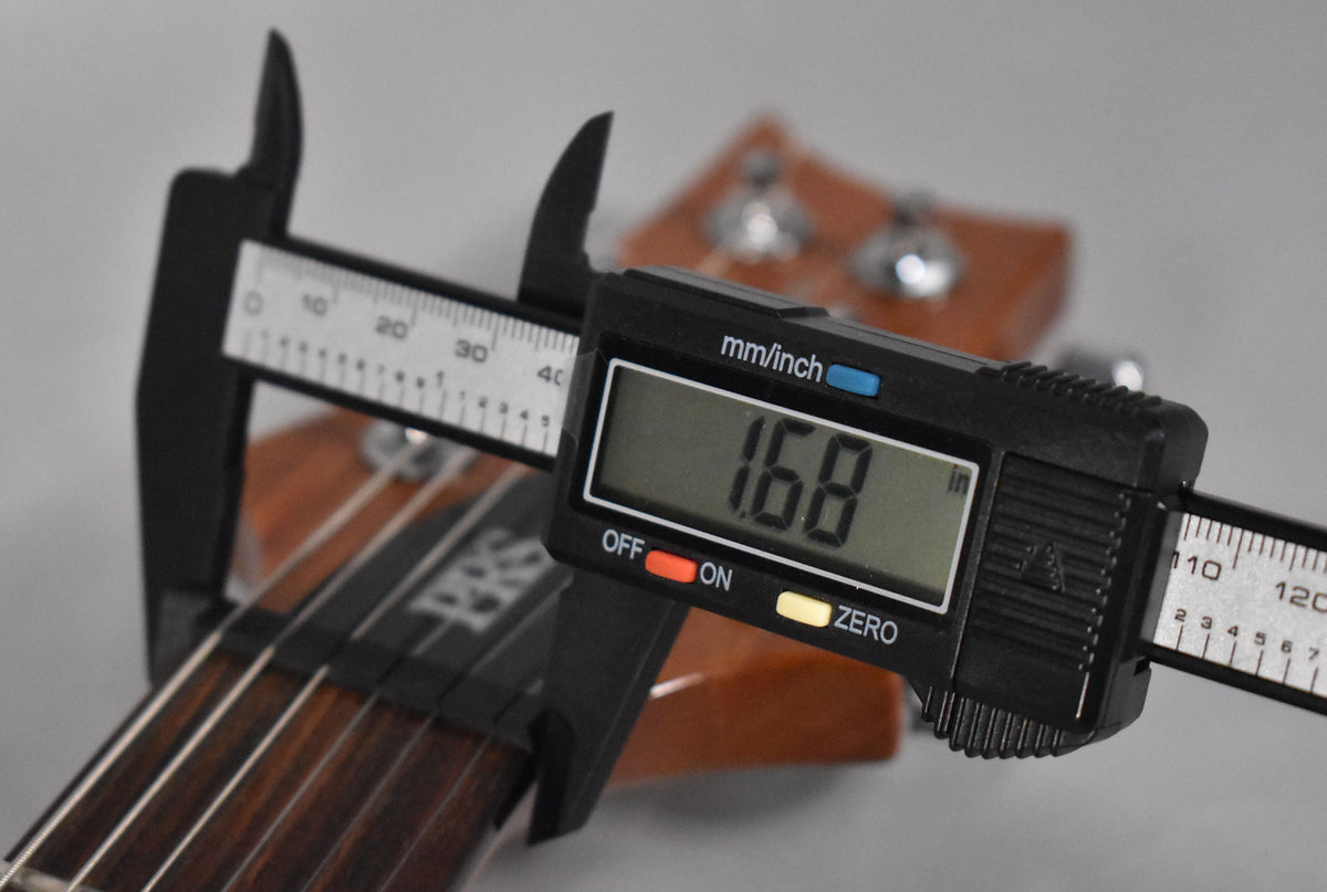 A digital caliper measures the nut width of the dark rosewood fretboard at 1.68 inches, with the headstock visible in the background.