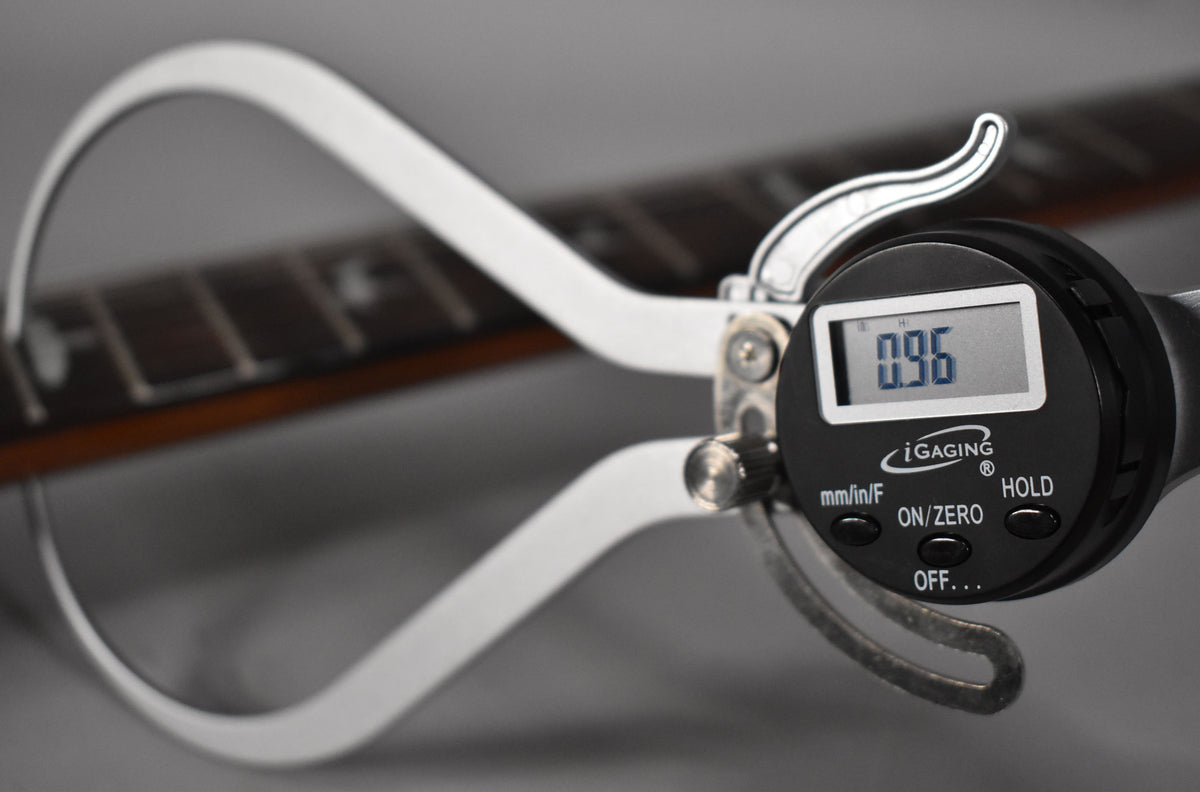 A digital caliper measures the fret height on the dark rosewood fretboard, displaying "0.96" mm.