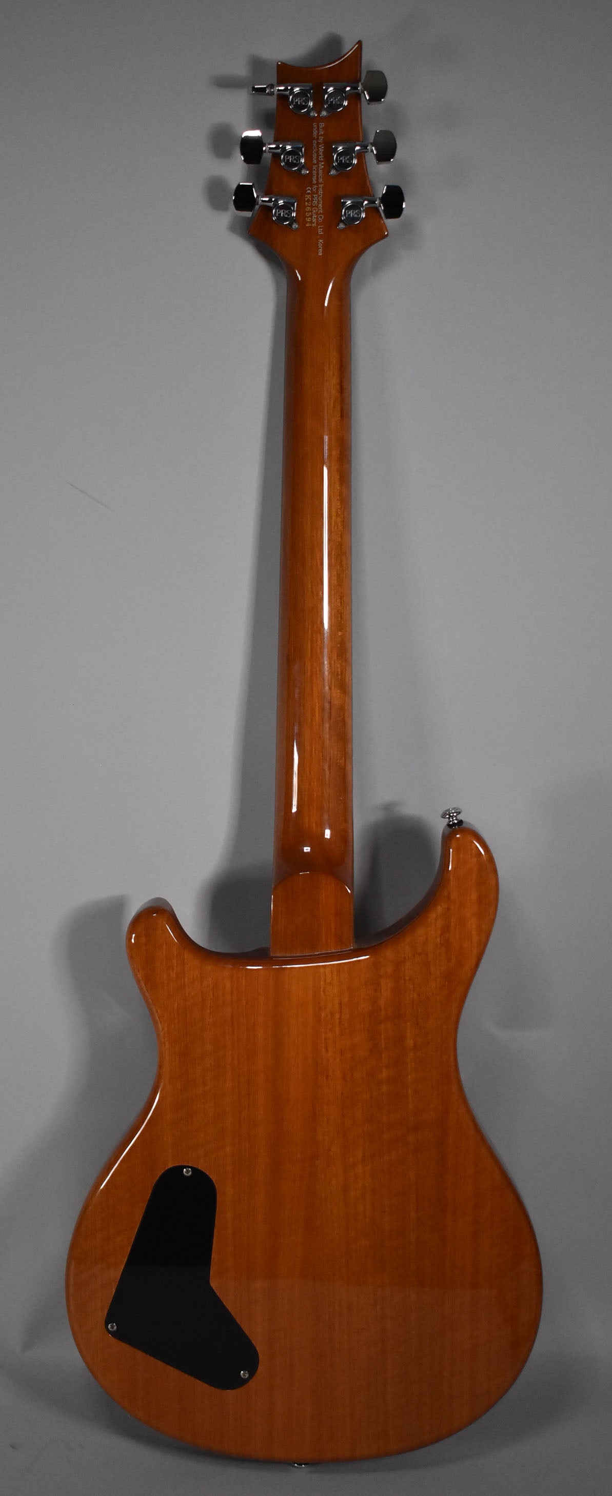 The back of a sunburst electric guitar, showing the glossy brown body, neck, headstock with six tuners, and a black control plate.