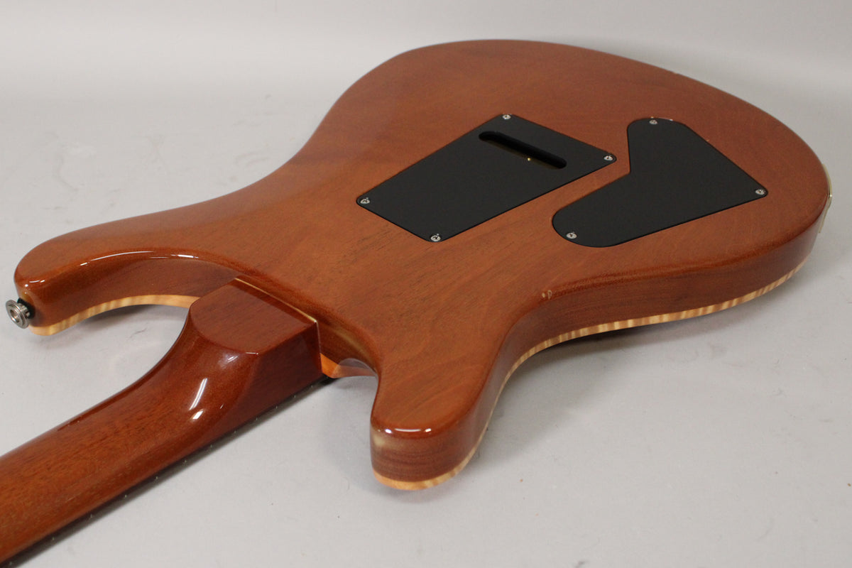 The back of a sunburst electric guitar, showing the neck joint, two black control cavity covers, and light edge wear.