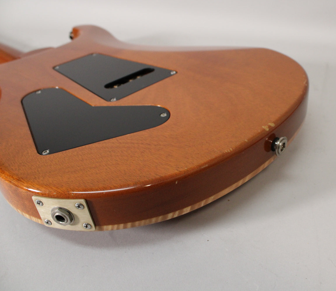 Rear view of the guitar body, showing two black control cavity covers, a strap button, and output jack, all on a glossy sunburst finish.