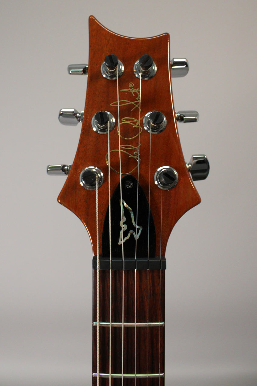 Close-up of the guitar's sunburst headstock with chrome tuners, black truss rod cover with a mother-of-pearl bird inlay, and dark fretboard.