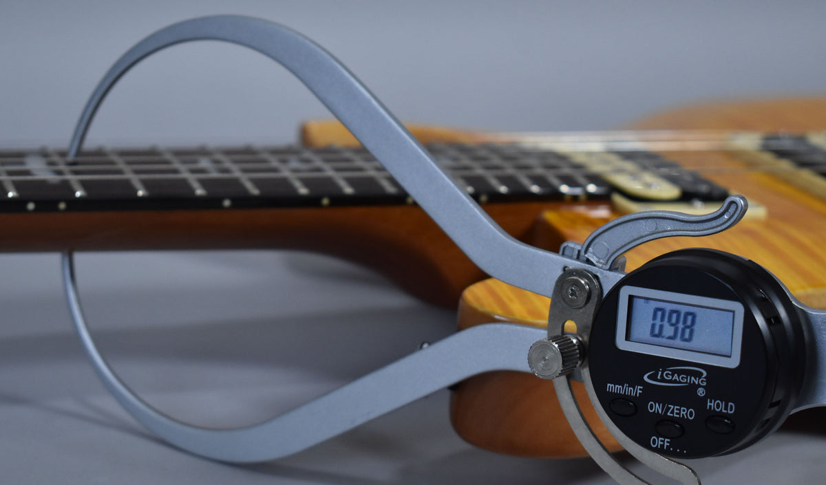 A digital caliper measures the neck relief at 0.98mm, with the Santana Yellow guitar's fretboard and body visible in the background.