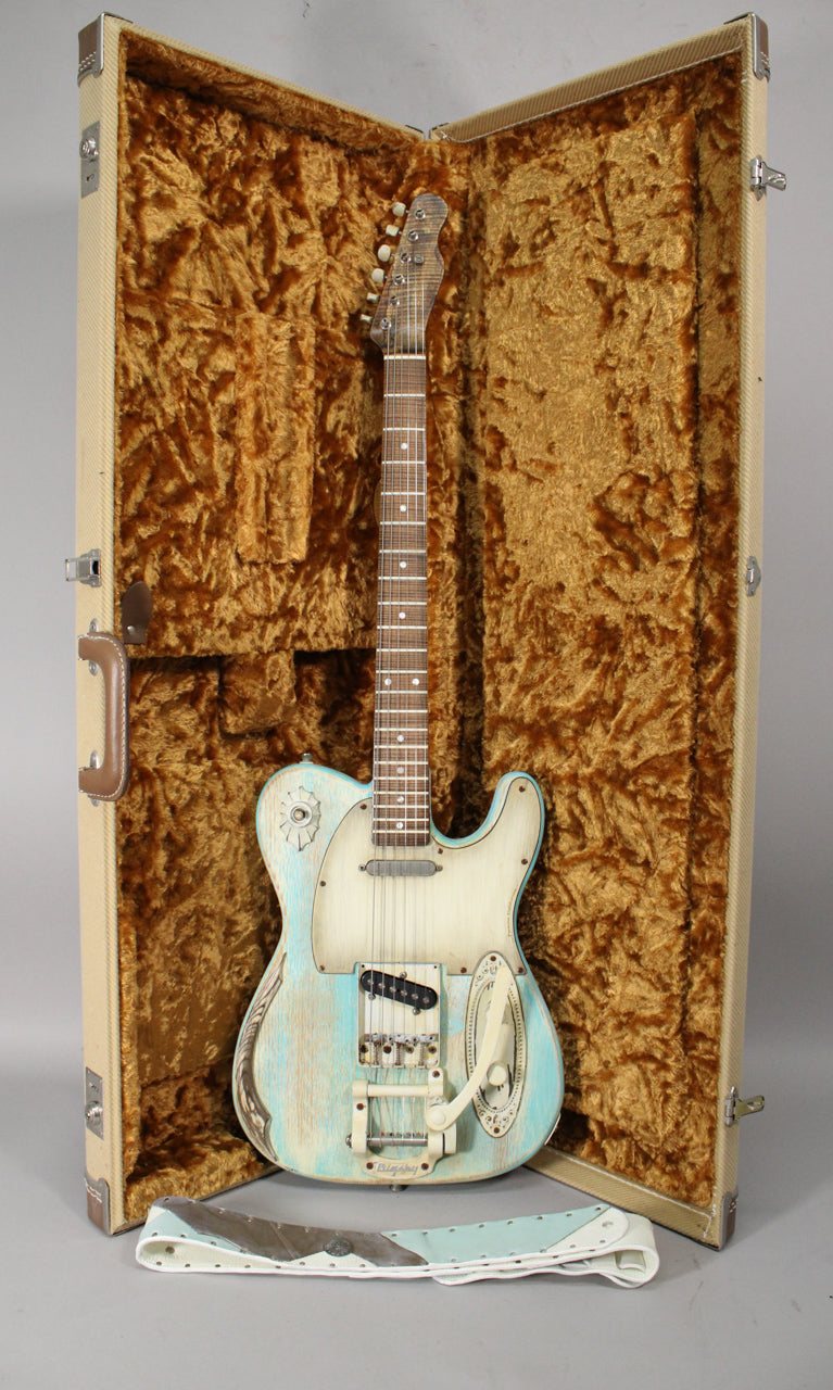 Full view of a light blue and white relic'd guitar with a Bigsby tremolo, resting in a tweed case with gold crushed velvet lining.