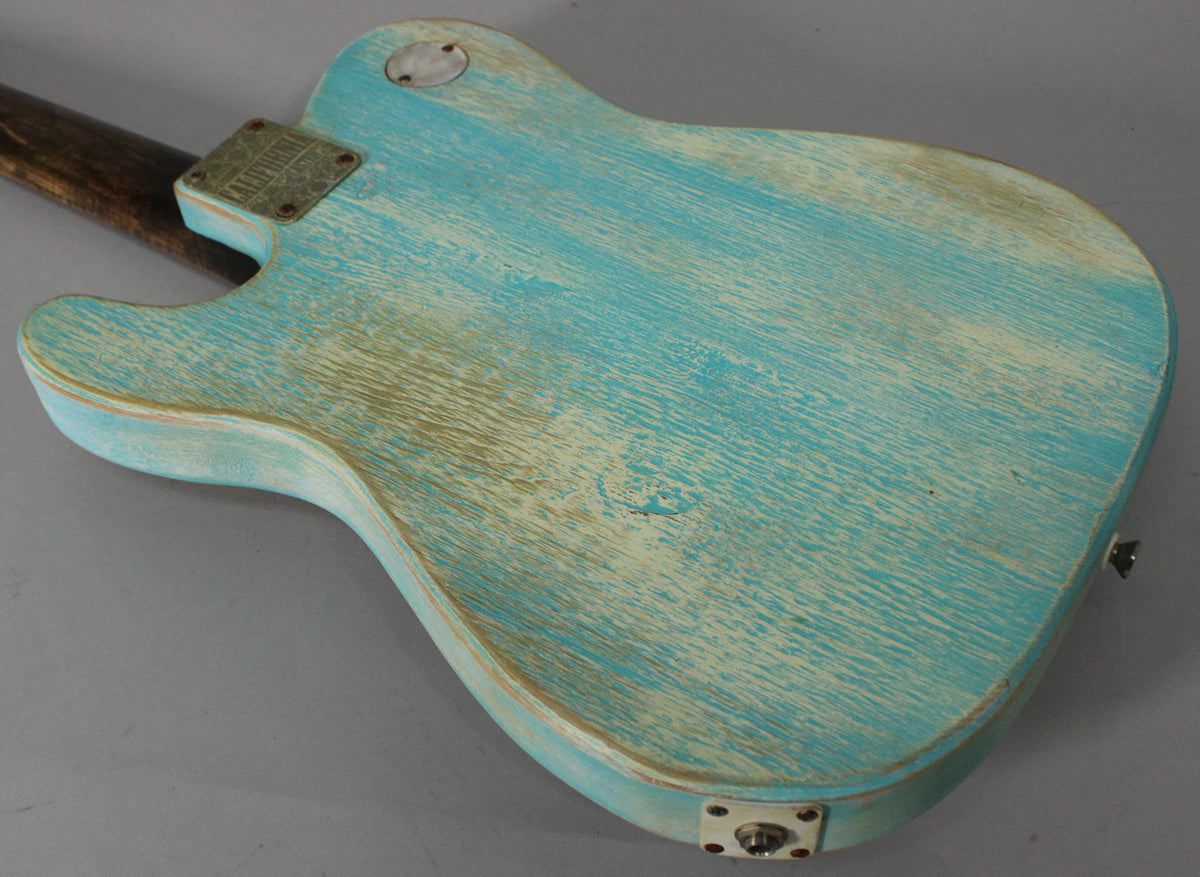The guitar's back shows heavy relic wear on its blue finish, revealing light wood grain, with a neck plate and output jack.