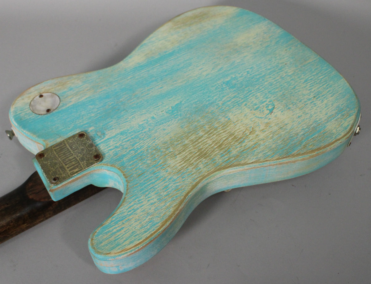 The guitar's back shows heavy relic wear on its blue finish, revealing the wood grain and a brass neck plate.