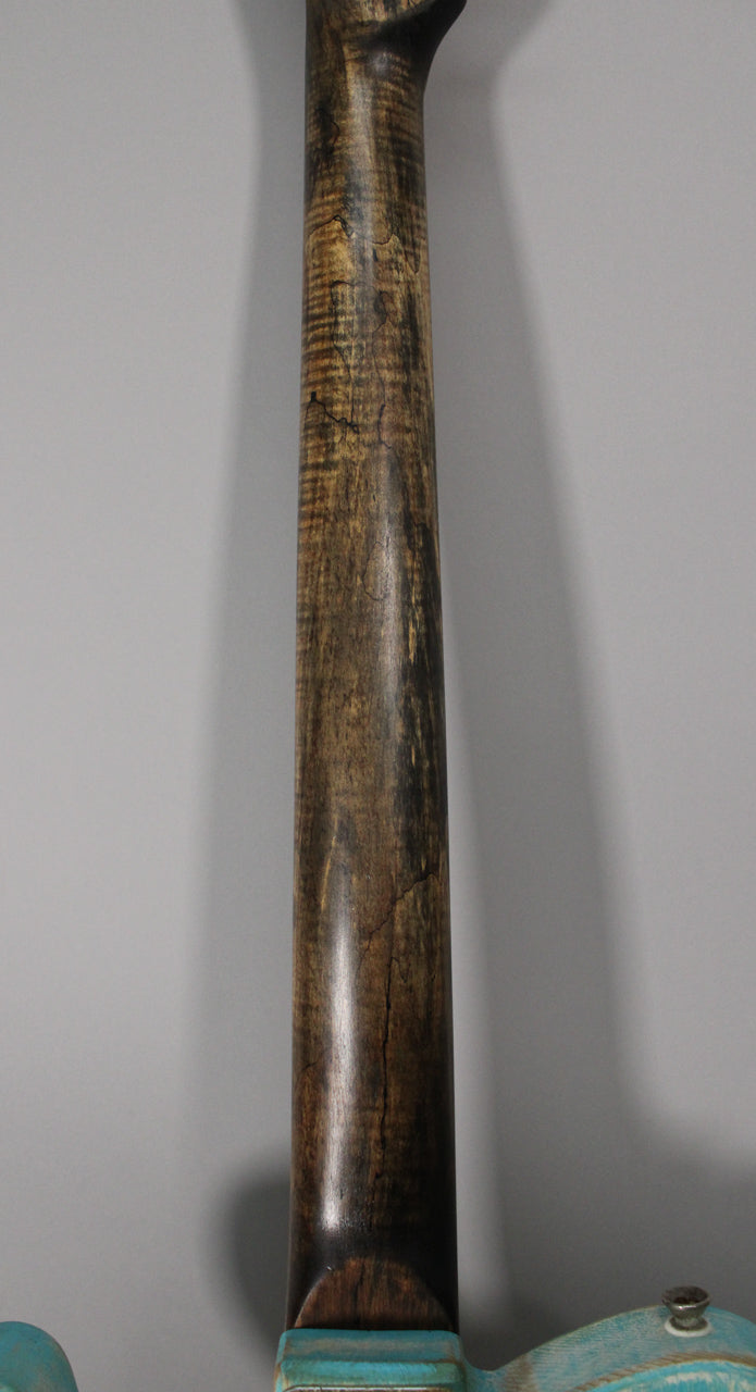 The guitar's heavily relic'd neck, with dark brown and tan wood grain and deep finish checking, extends from a light blue body.
