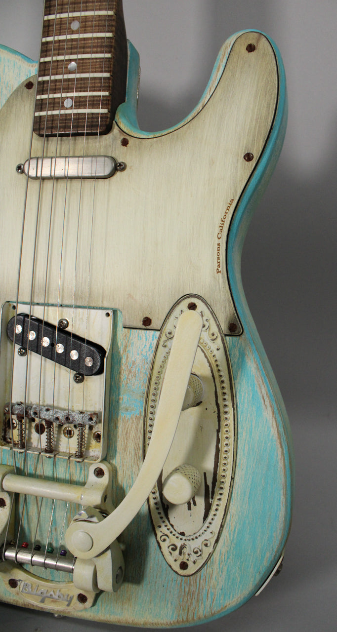 Close-up of a heavily relic'd blue and cream guitar body, showing a Bigsby tremolo, bridge humbucker, and ornate control plate.